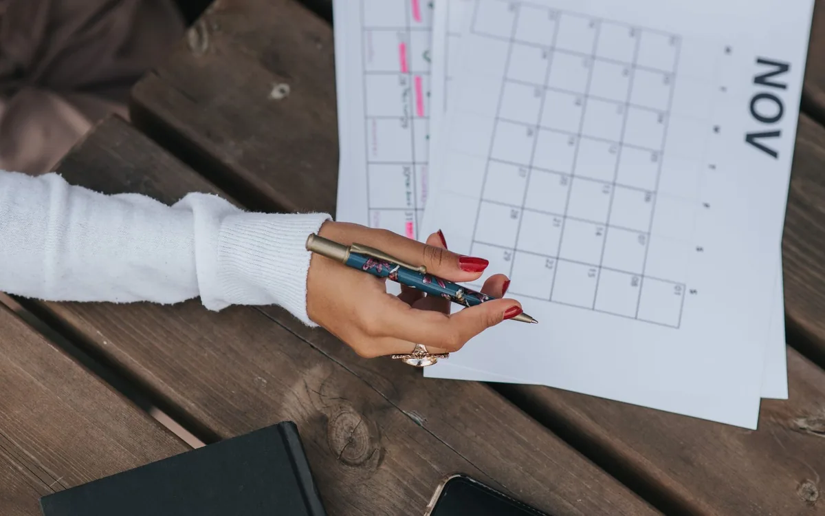 Mão com caneta sobre folhas de calendário do mês de novembro.