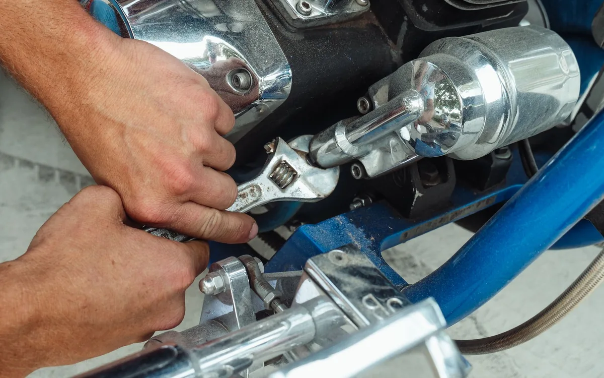 Mãos de mecânico trabalhando no motor de uma motocicleta.