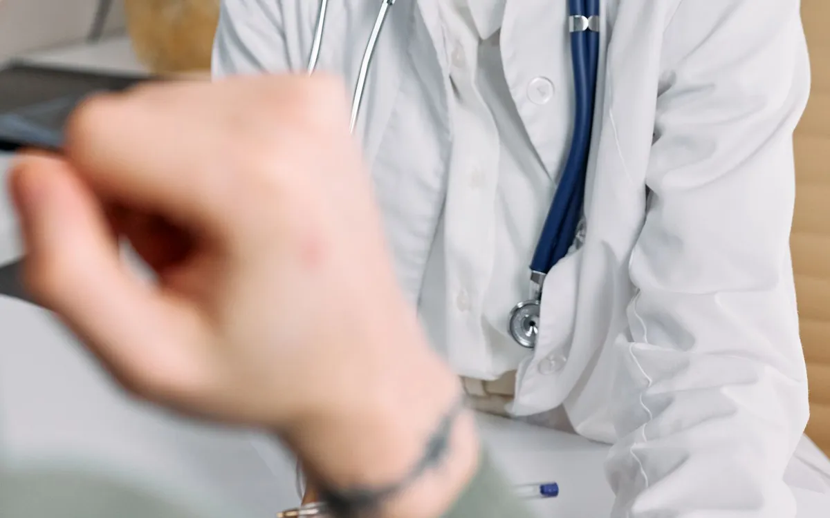 Médica de jaleco e estetoscópio sorrindo durante a consulta.
