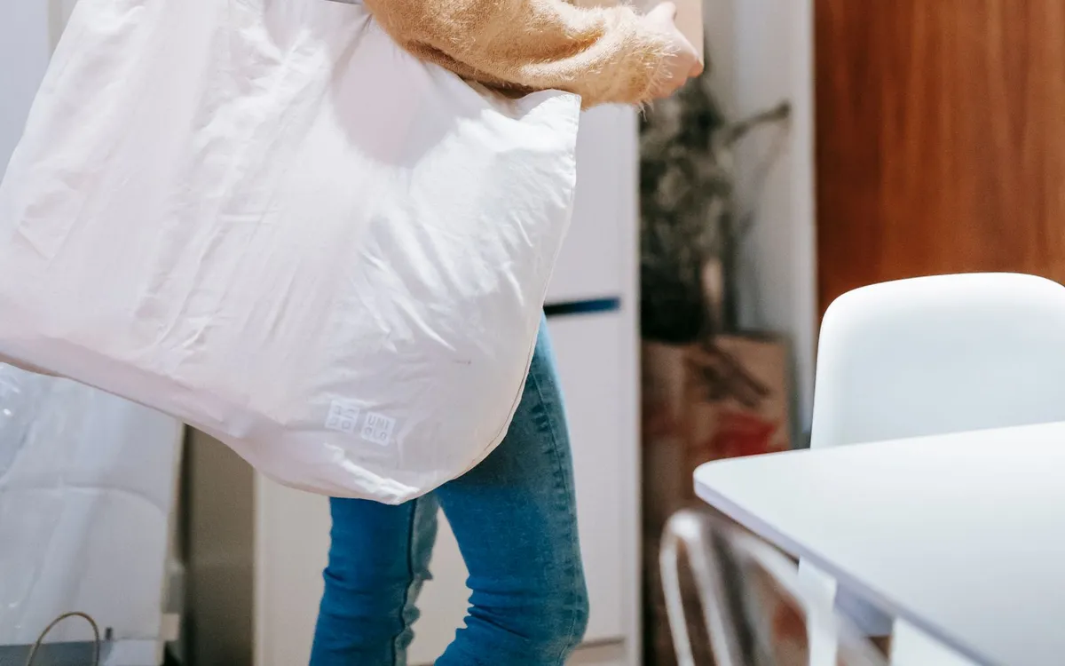 Mulher carregando caixas e uma sacola grande para fazer uma entrega.