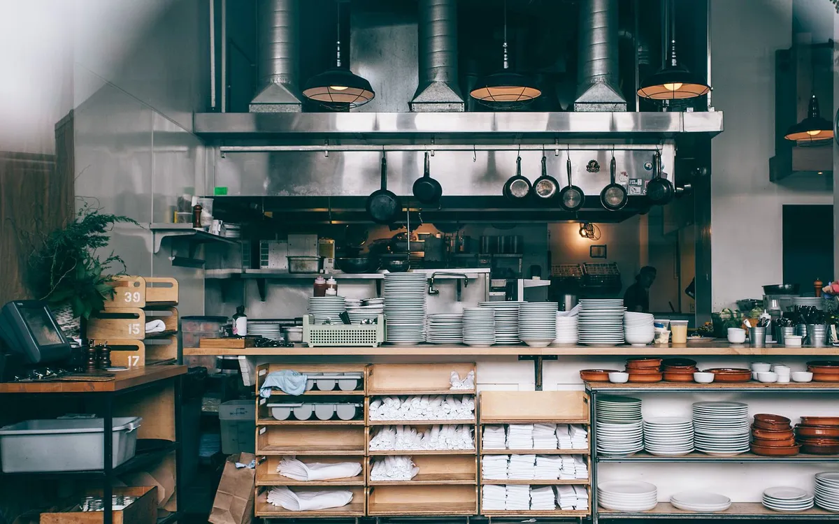 Cozinha profissional de restaurante com prateleiras de louças e utensílios.