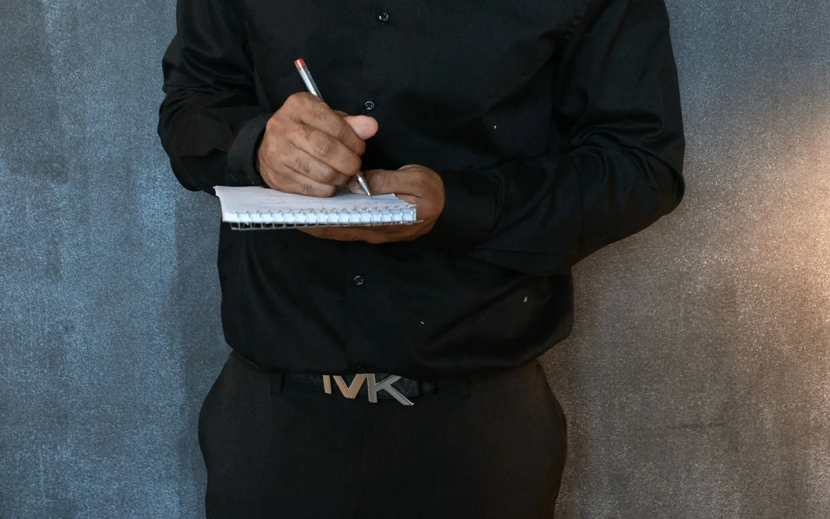 Homem anotando valores em um caderno.