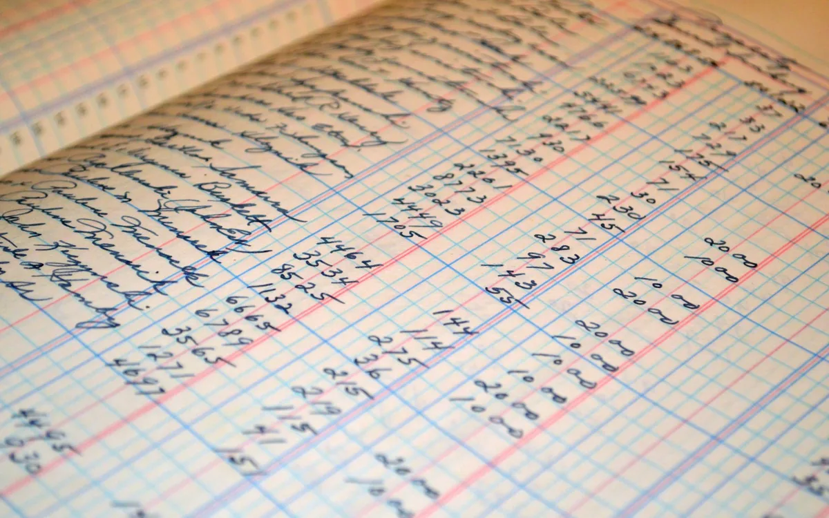 Livro de registros com anotações de valores.