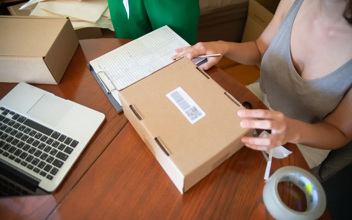 Lojista preparando pedidos e embalagens para envio.