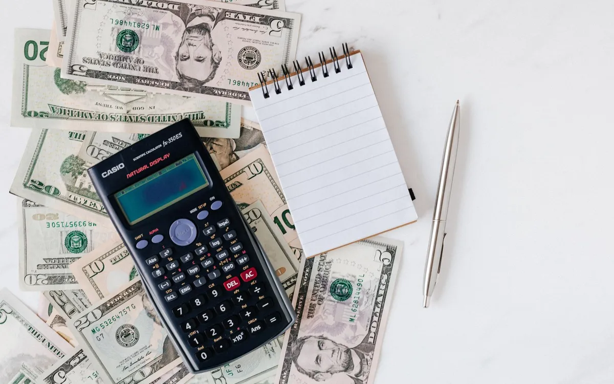 Calculadora e caderno de anotações sobre notas de dinheiro.
