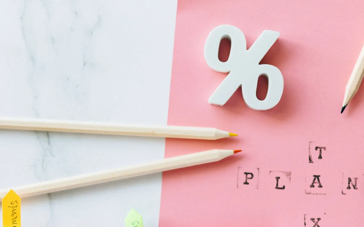 Agenda com marcadores coloridos, pastas e a palavra PLAN sobre fundo rosa.
