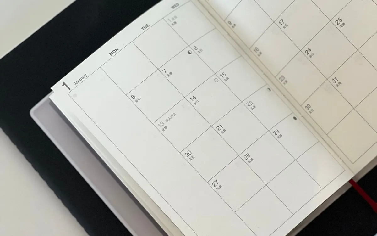 Agenda de calendário aberta sobre a mesa, com uma caneta ao lado.