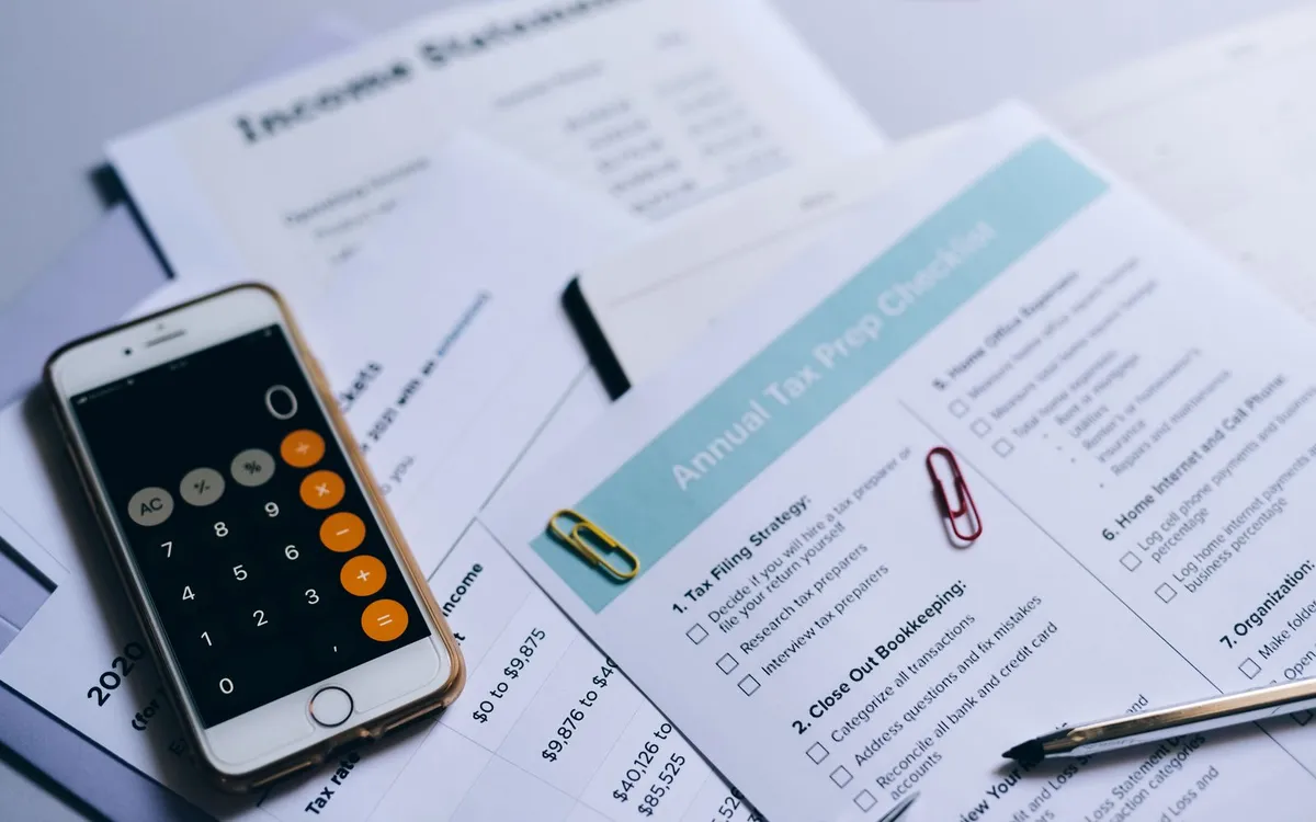 Celular com calculadora sobre um formulário de declaração de renda.
